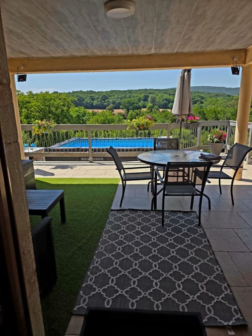 Überdachte Terrasse der La Maison de la Colline mit Esstisch, Pool und Ausblick auf die französische Landschaft bei Vers