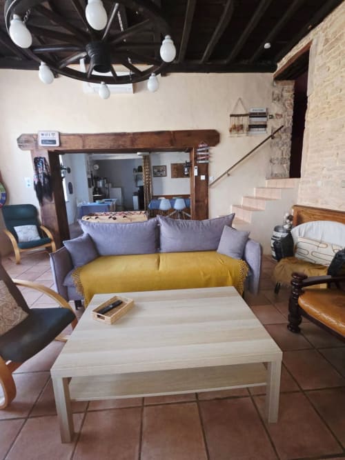Gemütliches Wohnzimmer der Maison de la Colline in Vers, Frankreich mit violettem Sofa, gelbem Plaid und modernem Kronleuchter