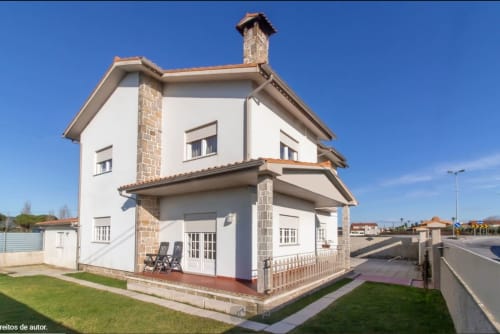 Fachada do hostel Sleep & Go em Esposende, Portugal - edifício moderno branco com chaminé de tijolos e jardim verde