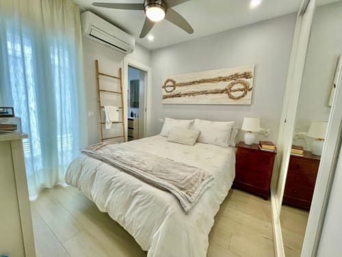 Moderno dormitorio en Solana Urban Lux en Fuengirola con ropa de cama blanca, mesitas de madera, ventilador de techo y vistas a la ciudad