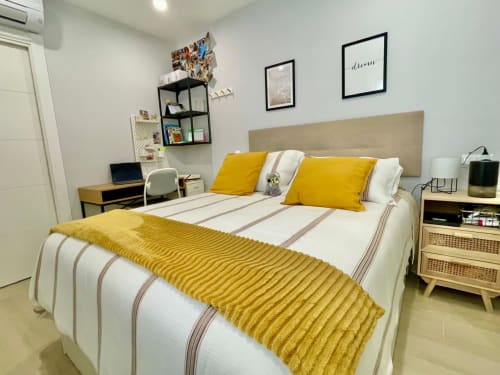 Dormitorio Solana Urban Lux en Fuengirola con acentos amarillos, cama confortable, escritorio y vista a la ciudad