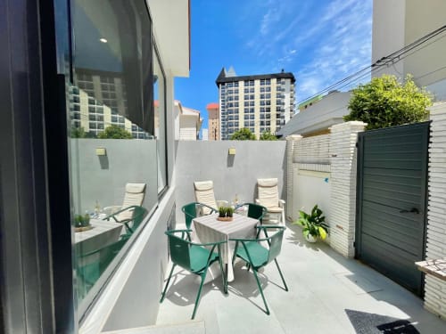 Terraza Solana Urban Lux en Fuengirola con sillas turquesas, mesa de comedor y vistas al skyline de la ciudad