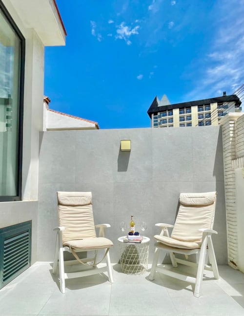 Terraza Solana Urban Lux en Fuengirola con dos tumbonas color crema, mesita auxiliar y vistas al skyline de la ciudad