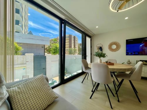 Moderna zona de comedor en Solana Urban Lux, Fuengirola con vistas a la ciudad, muebles contemporáneos y acceso a balcón