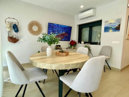 Comedor moderno en cottage Solana Urban Lux, Fuengirola con mesa redonda de madera, sillas beige y vista a la ciudad