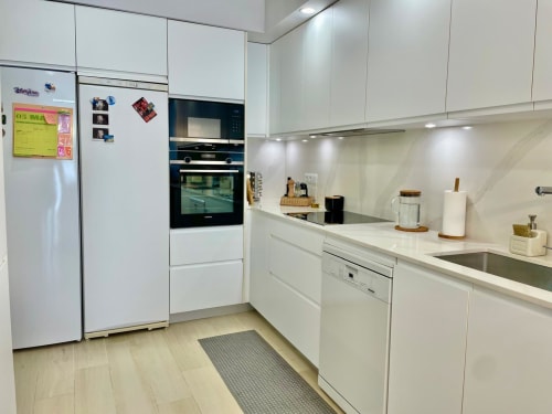 Cocina moderna blanca en apartamento Solana Urban Lux, Fuengirola con electrodomésticos acero inoxidable y encimeras mármol