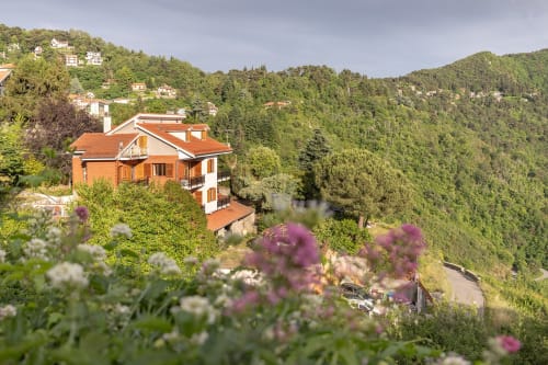 Hôtel Allegria à Bajardo, architecture de brique orange, niché dans une forêt avec jardins fleuris