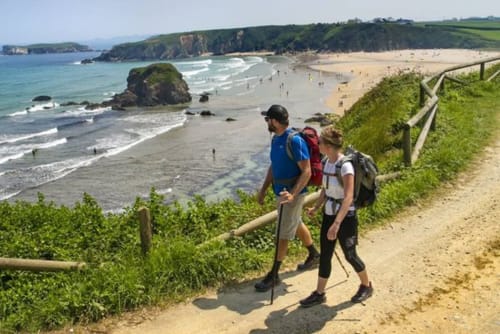 Dois caminhantes com mochilas trilhando a costa perto de Esposende, Portugal, com praia, falésias e oceano