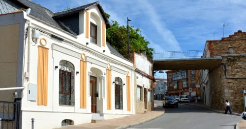 Fachada del hotel La Posada de las Flores con arquitectura colonial española, portada blanca y contraventanas doradas