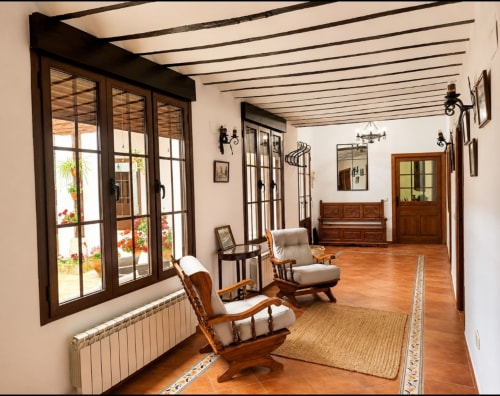 Interior espacioso de Casa Rural La Herrería con suelos de barro, vigas de madera y mobiliario rústico en Colmenar