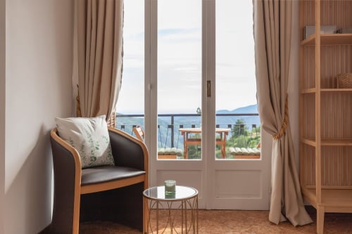 Suite Benessere à l'hôtel Allegria, Bajardo : chambre élégante avec accents bois, balcon vue mer, rideaux beige et atmosphère chaleureuse