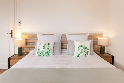 Chambre Benessere de l'hôtel Allegria à Bajardo avec literie blanche, coussins botaniques verts et tête de lit en bois