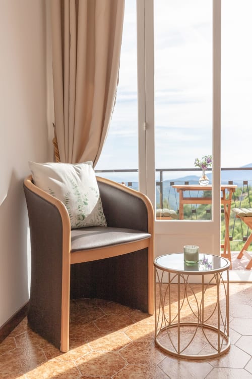 Coin salon confortable dans une chambre de l'hôtel Allegria avec vue sur les montagnes depuis le balcon à Bajardo