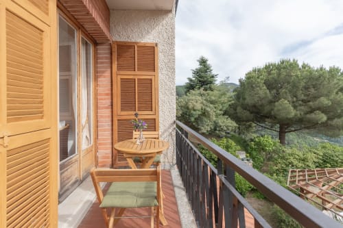 Balcon avec chaise et table en bois à l'hôtel Allegria à Bajardo, vue sur les montagnes et pins