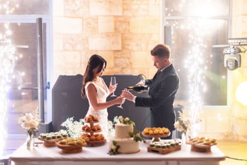 Couple trinquant au champagne à la célébration du Château ERIGOYE, élégante présentation de desserts et décor de pierre