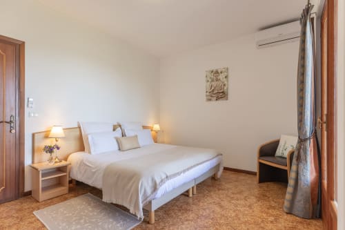 Chambre Calma de l'hôtel Allegria à Bajardo, Italie, avec lit double aux draps blancs et tables de nuit en bois