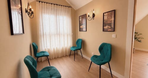 Elegante sala de espera en La Posada de las Flores con sillas de terciopelo turquesa, paredes crema e iluminación natural desde ventanales