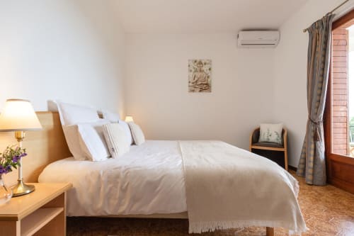 Chambre Calma à l'hôtel Allegria à Bajardo : literie blanche, vue montagne, climatisation et mobilier en bois.