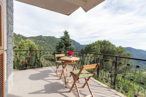 Balcon de la Chambre Calma à l'hôtel Allegria avec vue sur les montagnes, mobilier en bois et paysage verdoyant de Bajardo