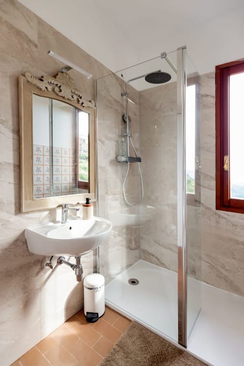 Salle de bain moderne de la Chambre Calma à l'hôtel Allegria, Bajardo, avec murs en marbre, douche à l'italienne et vue sur la montagne
