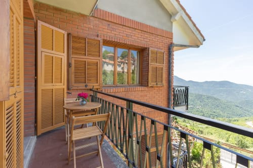 Balcon de la Chambre Felice à l'hôtel Allegria à Bajardo avec volets en bois, vue sur les montagnes et mobilier extérieur