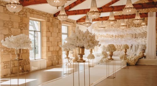 Elegant event space at Château ERIGOYE with cream floral arrangements, wooden beams, and crystal chandeliers in