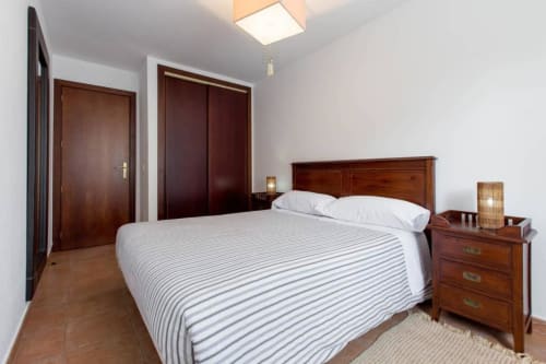 Espacioso dormitorio en apartamento rural Alojamientos Botica con muebles de madera, ropa de cama a rayas y piso de barro en La