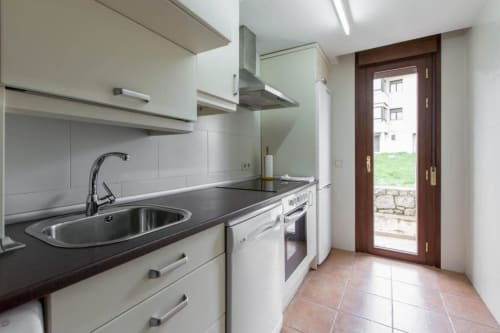 Cocina moderna en apartamento Alojamientos Botica Rural, La Cabrera, con encimera negra y electrodomésticos de acero inoxidable