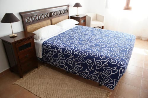 Dormitorio espacioso en Alojamientos Botica Rural con cama de madera, edredón azul estampado, mesitas de noche, lámparas y piso de baldosas