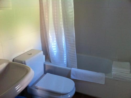 Baño con inodoro, bañera, ducha, toallas y artículos de aseo en el apartamento rural Alojamientos Botica en La Cabrera