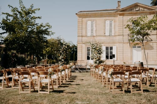 Outdoor wedding ceremony setup at Château ERIGOYE with wooden chairs and white flowers in Beychac-et-Caillau