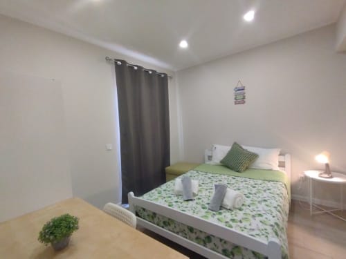 Современная спальня с зелеными листовыми постельными принадлежностями в хостеле Furnaka Village в Луринье, Португалия, с темными шторами