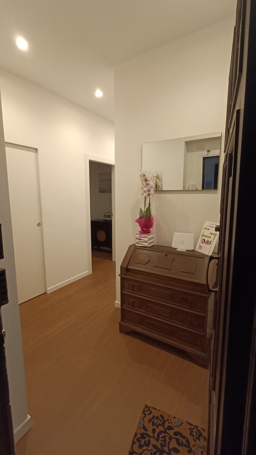Corridoio moderno dell'appartamento Roma Casa Tua con comò in legno, porte bianche e parete a specchio