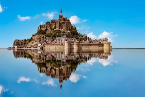 Le château du Mont-Saint-Michel se reflétant dans l'eau sous un ciel bleu, Normandie France