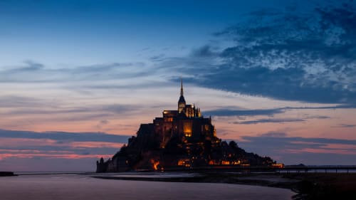Le Mont Saint-Michel illuminé au crépuscule avec les eaux de la marée, Normandie France