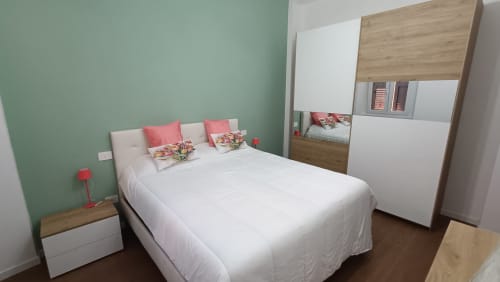 Camera Annarella Maison di Roma Casa Tua con pareti verde menta, letto bianco, dettagli corallo, armadio in legno e vista sulla città