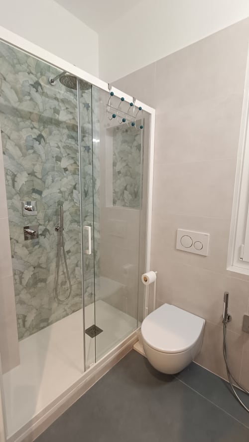 Bagno moderno in Roma Casa Tua con doccia in marmo, wc sospeso e pavimento scuro