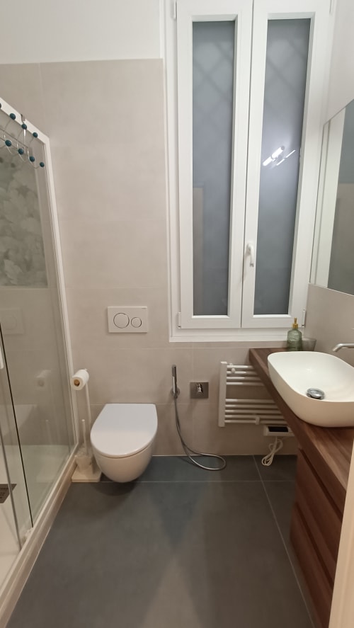 Bagno moderno nell'appartamento Annarella Maison di Roma Casa Tua con WC bianco, lavabo a ciotola, doccia e vetro satinato