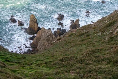 Côte normande sauvage avec rochers escarpés, vagues turquoise et falaises herbeuses à Skol en Normandie