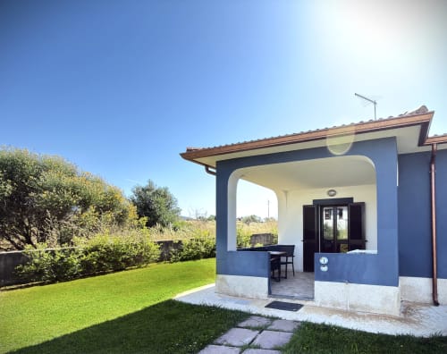 Villa bianca e blu con patio coperto presso A Mare Case Vacanze a Valledoria, con vista su lussureggiante giardino con prato verde