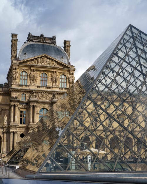 Pyramide de verre du Louvre devant un bâtiment en pierre classique, décor de luxe à Paris