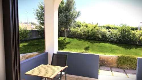 Patio privato con tavolo in legno con vista su lussureggiante giardino della villa Villetta 2 a Valledoria