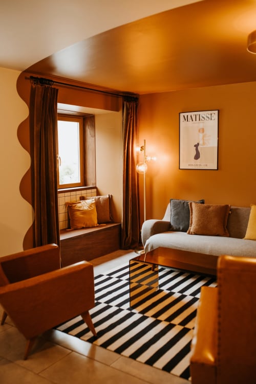 Chambre chaleureuse orange du gîte Les Granges De Pil Bara à Langoat avec tapis rayé et coin fenêtre