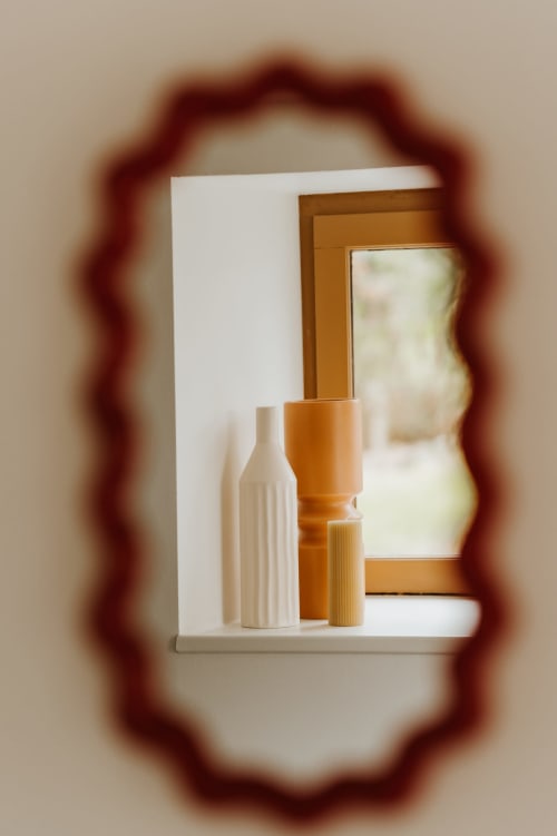 Miroir à cadre en bois décoratif reflétant des vases en céramique blanche et des éléments en bois au gîte Les Granges De Pil Bara