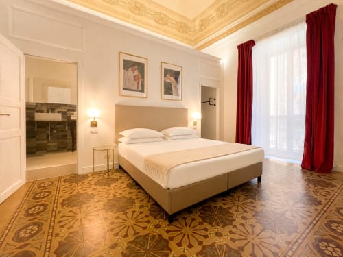 Camera King Superior elegante presso Casa Beretti Catania con testata beige, soffitto ornato, pavimenti in marmo e velluto rosso