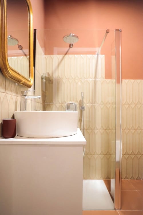 Modern bathroom at Casa Beretti Catania with round white sink, coral walls, and shower enclosure