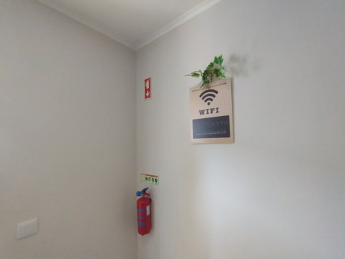 Hostelflur mit WiFi-Schild, Feuerlöscher und Pflanze im Furnaka Village in Lourinhã