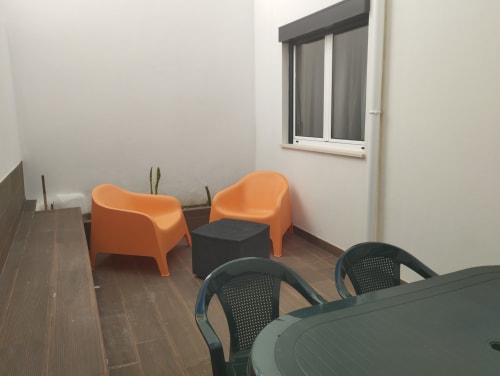 Außenbereich mit Sitzmöglichkeiten im Furnaka Village Hostel in Lourinhã mit orangefarbenen Stühlen und schwarzem Tisch