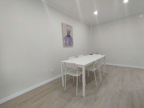 Modernes Esszimmer der Furnaka Village Herberge in Lourinhã mit weißem Tisch, Stühlen, Holzböden und lila Kunstwerk