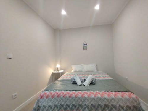 Gemütliches Zimmer in der Furnaka Village Herberge in Lourinhã mit Queensize-Bett, weißen Kissen, gemusterter Bettwäsche und moderner Beleuchtung